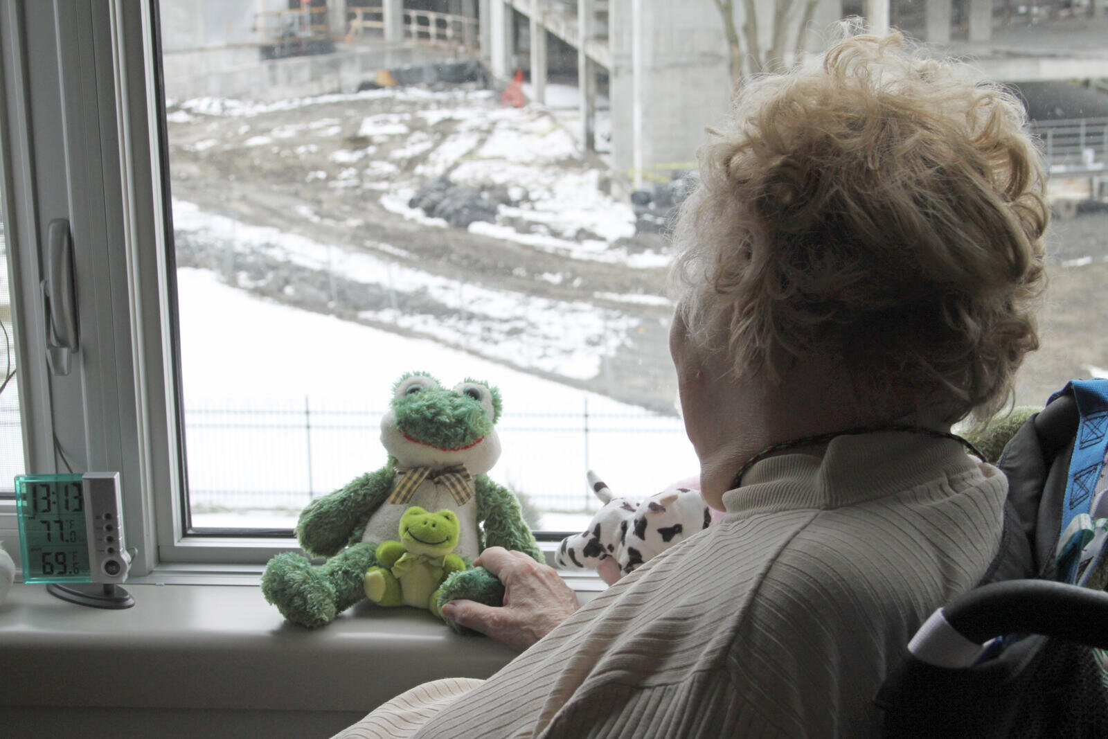 Eldre ensom kvinne titter ut gjennom vinduet.