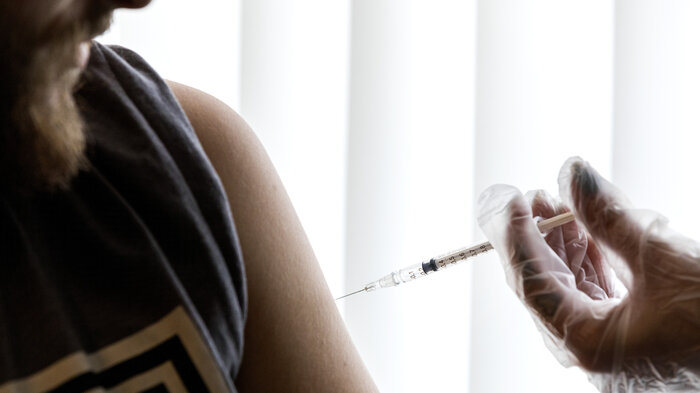 Bildet viser en mann som får en sprøyte med vaksine