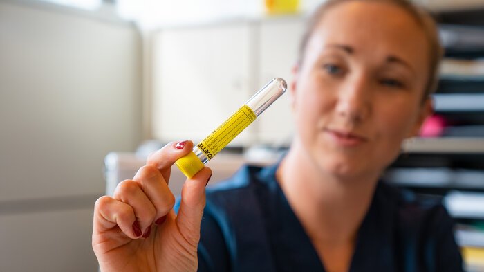 Bildet viser Monica Brun Løkkeberg som holder et prøveglass.