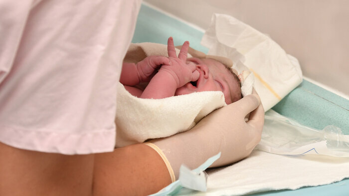 Bildet viser helsepersonell som holder i en nyfødt baby.