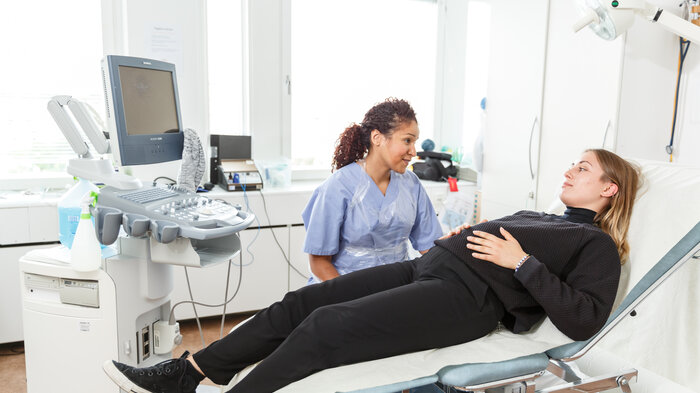 bildet viser en jordmor på jobb med gravid kvinne