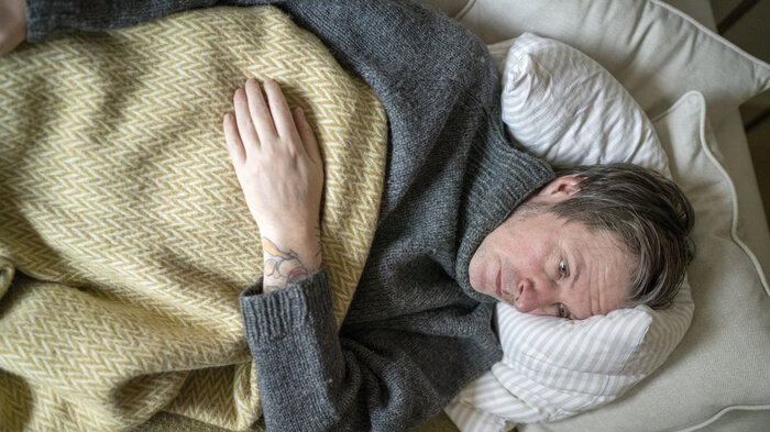 Illustrasjonsbilde av forkjølet mann på sofaen.