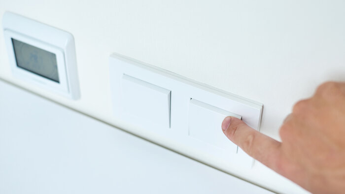 Bildet viser en finger som slår av en lysbryter.