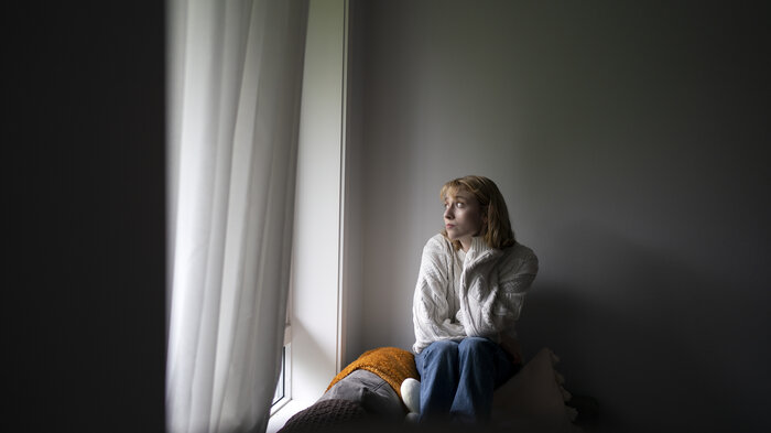 Bildet viser en kvinne som sitter ved et vindu.