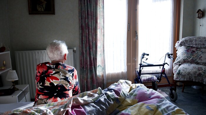 Bilde av eldre person på sengekanten på soverommet