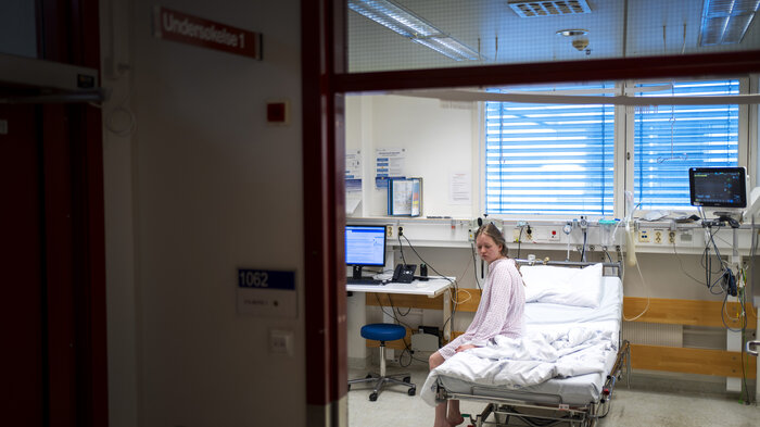 Bildet viser en pasient som sitter i en sykehusseng