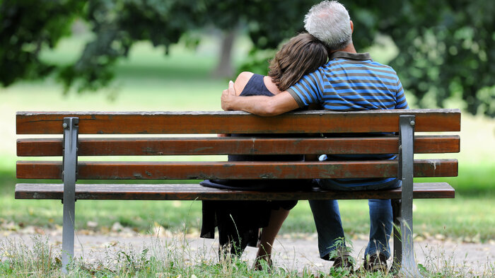 Bildet viser to mennesker som sitter på en benk sett bakfra.