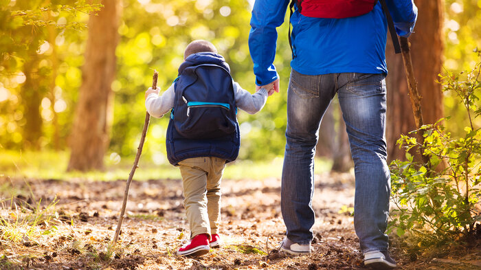Bilde viser et barn med sin far som går tur i skogen