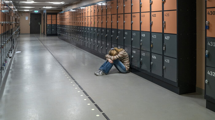 Bildet viser en ungdom som sitter i en korridor Bildet viser en ungdom som sitter i en korridor