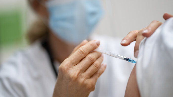 Bildet viser helsepersonell som setter en vaksine.