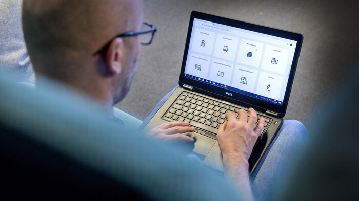 Bildet viser en mann som sitter med PC-en på fanget.