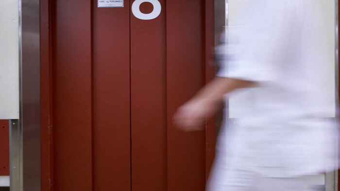 Bildet viser en sykepleier som beveger seg raskt i en korridor