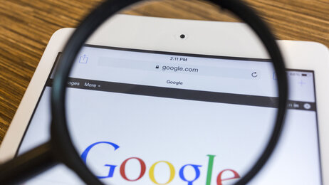  Bildet viser et forstørrelsesglass som holdes over Googles søkeside