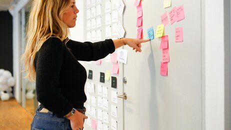 Bildet viser en kvinne som studerer post-it lapper klistret opp på en dør.