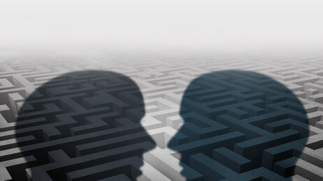 Bildet viser silhuetten av to mennesker som står ovenfor hverandre. I bakgrunnen kan man skimte en labyrint.