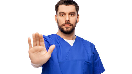 Bildet viser en mannlig sykepleier som viser håndflaten som et tegn på at nok er nok