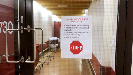 Bildet viser en stengt dør med et oppslag om at avdelingen ikke mottar besøk.