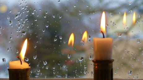 Bildet viser to stearinlys i et vindu