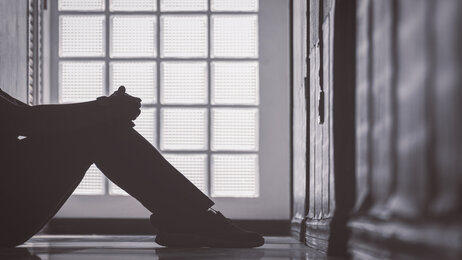 Bildet vise et utsnitt av et menneske som sitter på gulvet