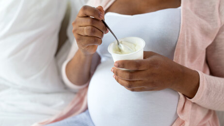 Bildet viser en gravid kvinne som spiser yoghurt