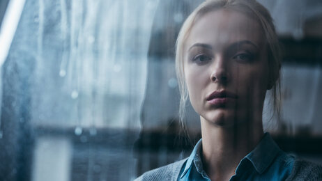 Bildet viser en trist kvinne som ser ut av et vindu. 