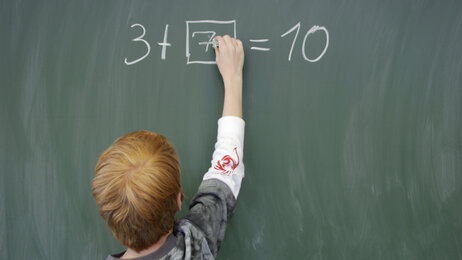 Bildet viser en elev som skriver på tavle.