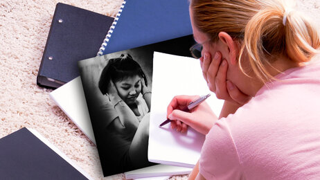 Bildet viser en student som sitter lent over en blokk med en penn. Blokken er tom for innhold og skrift.