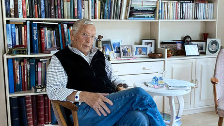 Bildet viser Torleif Parelius Lyngstad som sitter i en stol foran en bokhylle med masse bøker