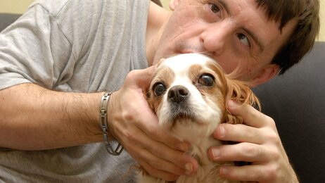 Mann med Downs syndrom koser med en hund.