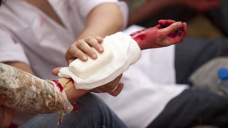 Kvinne gir førstehjelp til person som blør.