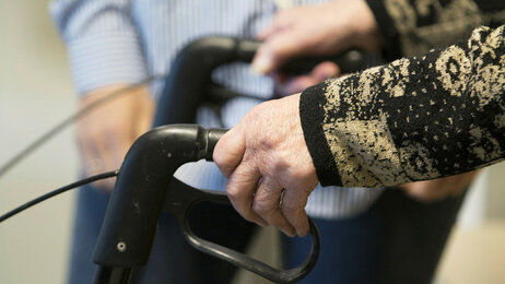 Bildet viser en gammel mann med gåstol.