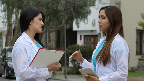 Bildet viser to unge kvinnelige sykepleiere som står ute og snakker sammen