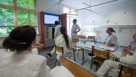 Bildet viser sykepleierstudenter ved Høgskolen i Oslo og Akershus inne i et undervisningsrom. Alle har uniformer på.