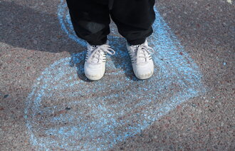 Bildet viser et barn som står på et hjertet - tegnet med kritt - i skolegården.
