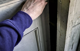 Bildet viser en arm som lukker en gammel dør