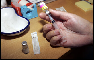 Bildet viser hender som trekker opp meslingvaksine.