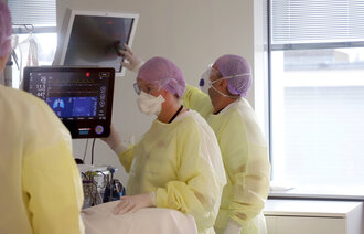 Bildet viser intensivsykepleiere inne på et pasientrom på Akershus universitetssykehus