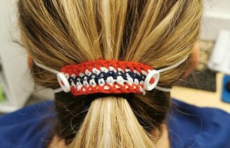 Bildet viser en slags hårspenne, heklet av bomullsgarn, med to knapper på.