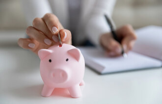 Bildet viser en som putter penger i en sparegris