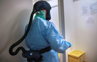 Bildet viser en intensivsykepleier med smittevernutstyr på jobb