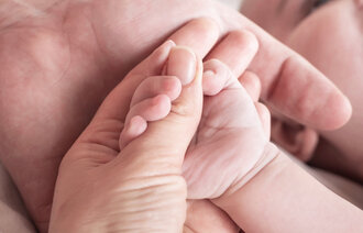 Bildet viser en nyfødt som holder rundt en finger til en voksen