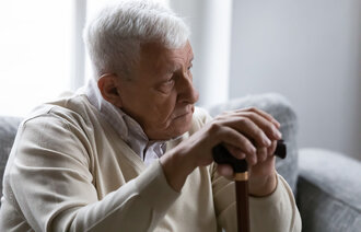 En eldre mann holder en stokk