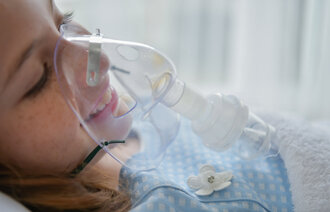 Bildet viser et barn med oksygenmaske foran ansiktet.