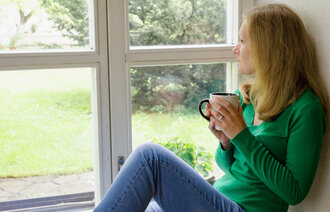 Bildet viser en kvinne som sitter og ser ut av et vindu.