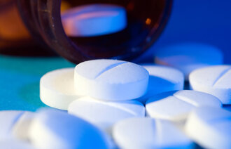 Bildet viser et glass med piller som ligger på siden, og som det er helt flere piller ut av.