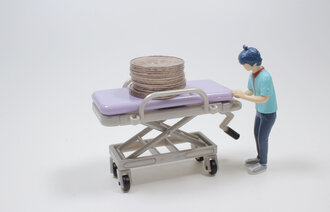 Bildet viser figurerer av en portør som triller en tom båre med mynter