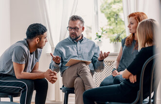 Bildet viser en lærer som sitter i en gruppe av ungdommer, på stoler i en sirkel