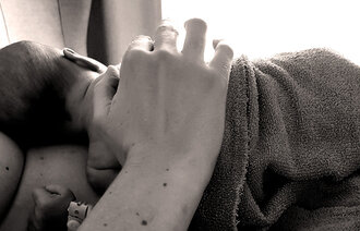 Bildet i sort og hvitt viser et nyfødt barn som ligger på mors mage.