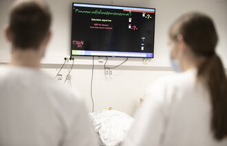 Bildet viser to sykepleiere som ser på en monitor.