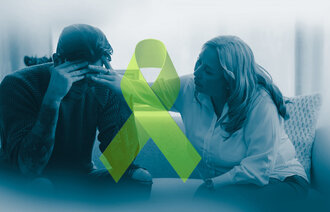 The photo shows a despaired man being comforted by a woman. Between them there is a green ribbon, the symbol of mental health